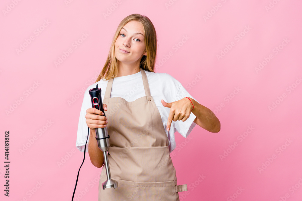 Young russian cook woman holding an electric mixer isolated points down with fingers, positive feeling.