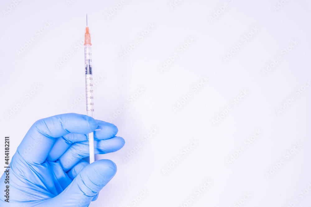Gloved hand of doctor or nurse holding syringe with liquid vaccine before injecting over white background.Covid19, Coronavirus Concept. Flue shot Gloved hand of doctor or nurse holding syringe with liquid vaccine before injecting over white background.Covid19, Coronavirus Concept. Flue shot