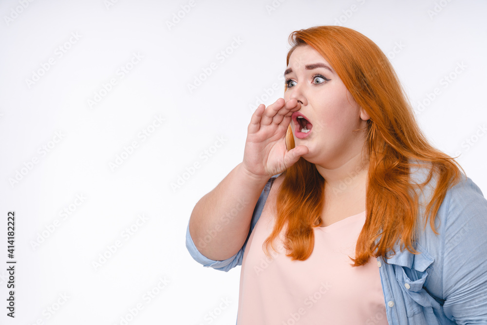 Fat woman with ginger hair announcing with the hand to make it louder isolated over white background Fat woman with ginger hair announcing with the hand to make it louder isolated over white background