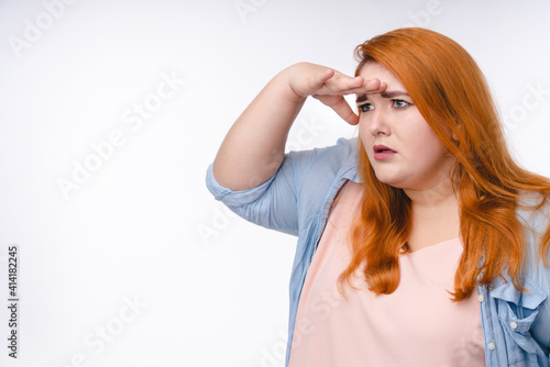 Plump redhead woman looking somewhere far away isolated over white background