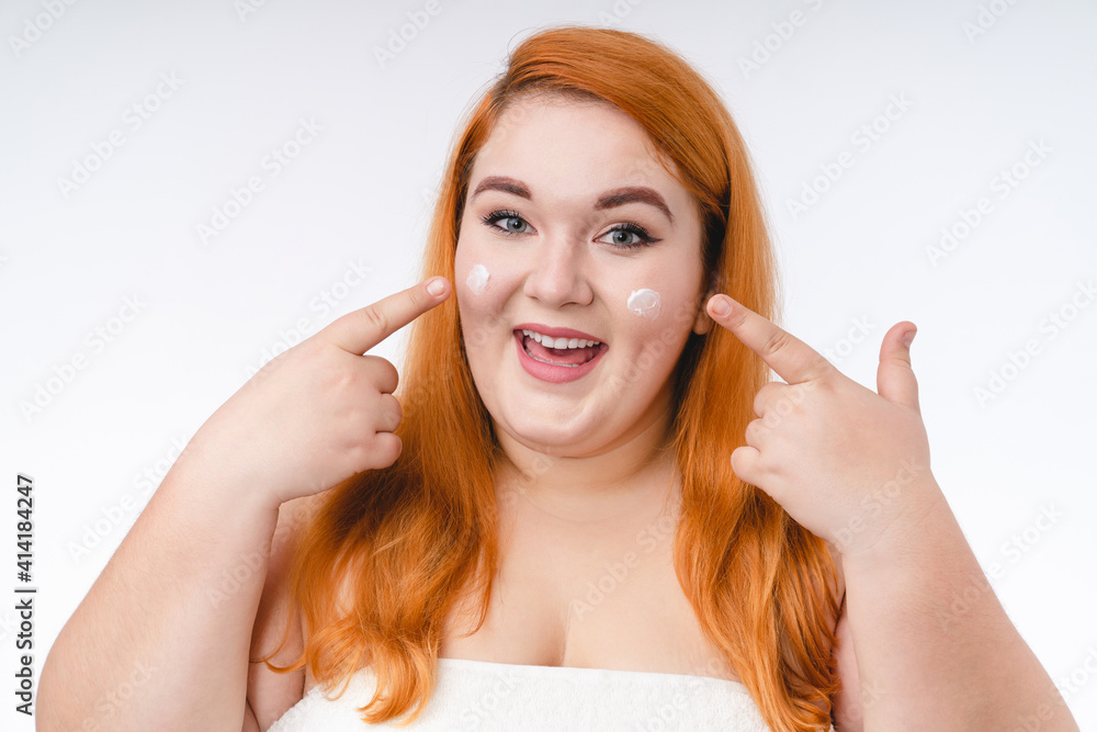 Smiling plump woman using body cream on her face isolated over white background Smiling plump woman using body cream on her face isolated over white background