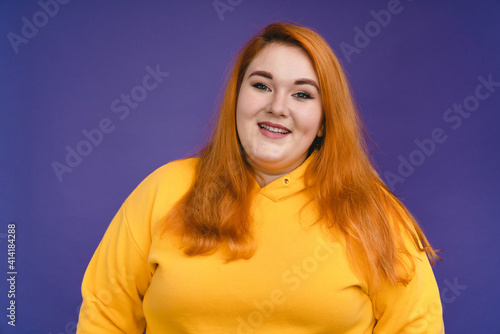 Portrait of a plump redhead woman isolated over blue background photo