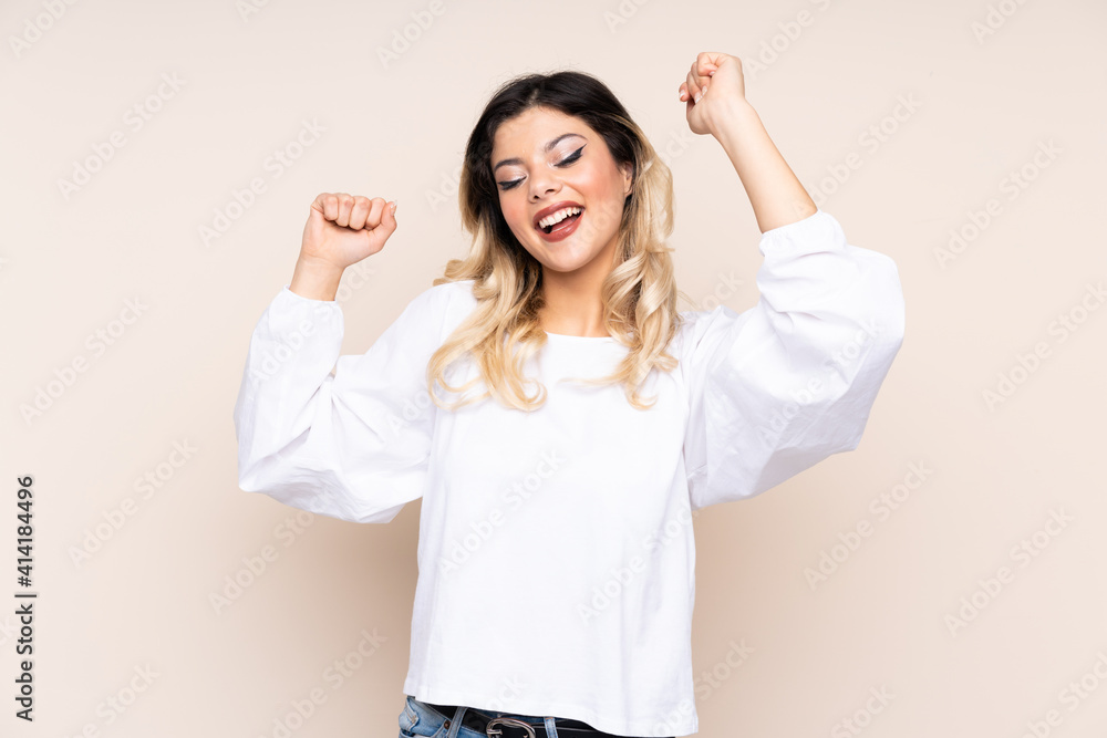 Teenager girl isolated on beige background celebrating a victory Teenager girl isolated on beige background celebrating a victory