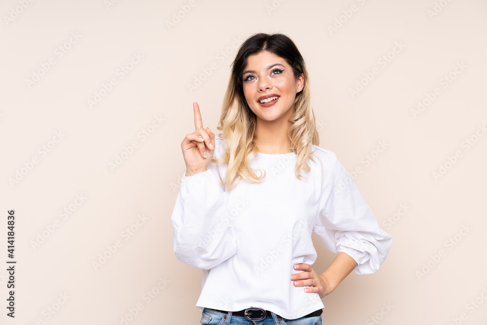 Teenager girl isolated on beige background showing and lifting a finger in sign of the best Teenager girl isolated on beige background showing and lifting a finger in sign of the best