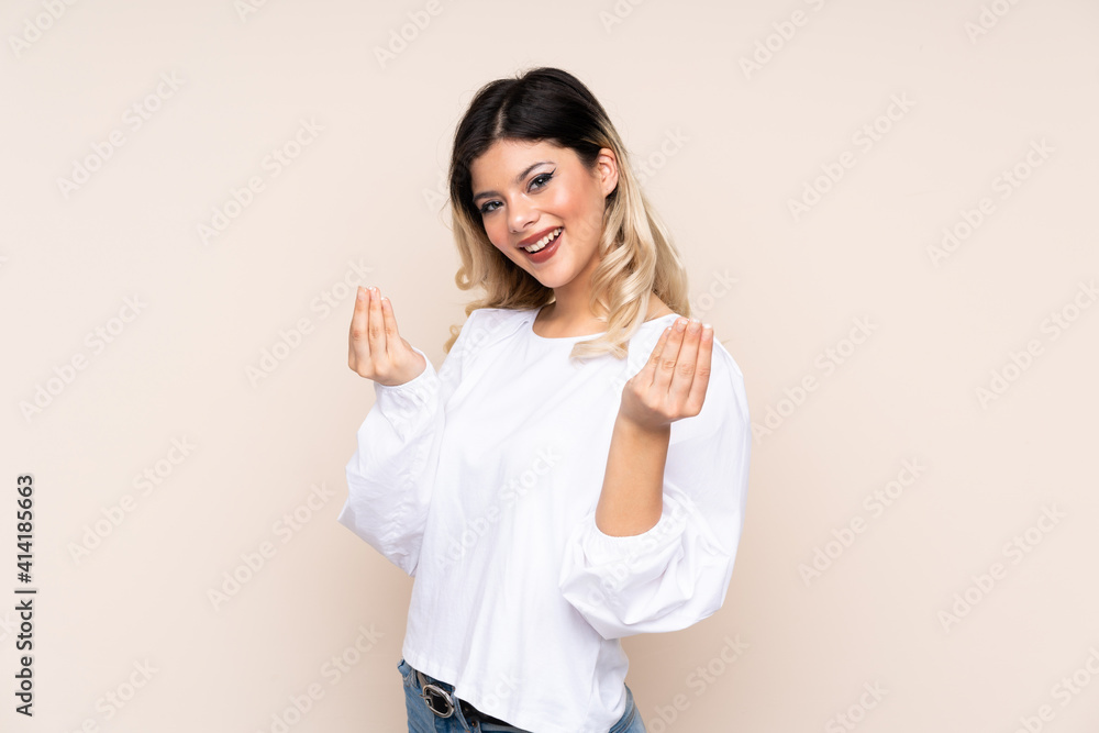 Teenager girl isolated on beige background making money gesture Teenager girl isolated on beige background making money gesture