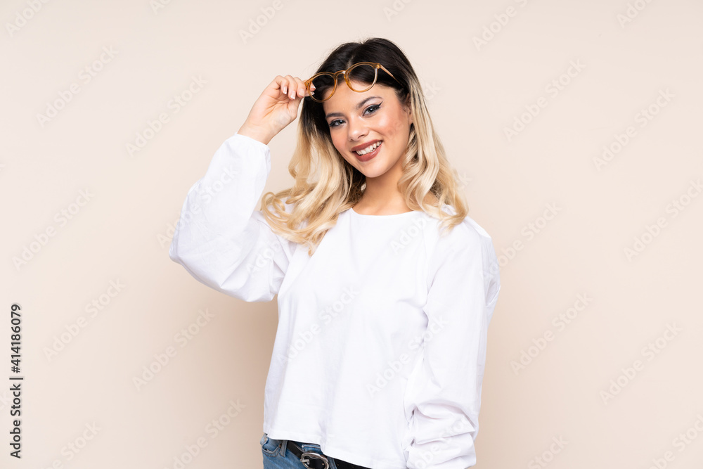 Teenager girl isolated on beige background with glasses and happy Teenager girl isolated on beige background with glasses and happy