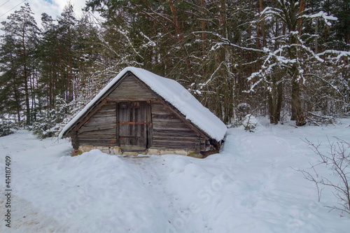 An old picturesque outbuilding near the forest in the village in winter.
