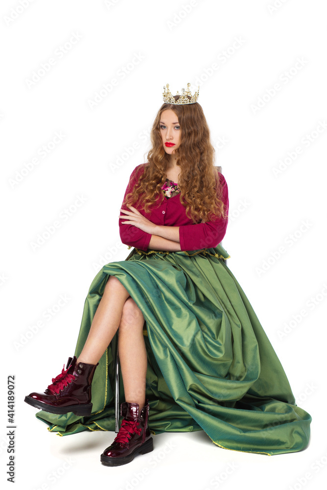 Fashion photo of a beautiful elegant young teenager girl with long curly hair in the crown and a pretty long green skirl isolated on white background.