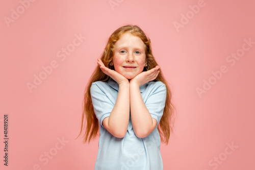 Cute posing. Happy, smiley redhair girl isolated on pink studio background with copyspace for ad. Looks happy, cheerful. Childhood, education, human emotions, facial expression concept.