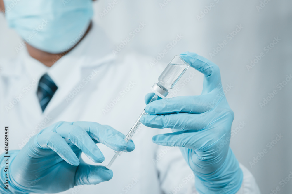 A doctor or scientist in the COVID-19 medical vaccine research and development laboratory holds a syringe with a liquid vaccine to study and analyze antibody samples for the patient. A doctor or scientist in the COVID-19 medical vaccine research and development laboratory holds a syringe with a liquid vaccine to study and analyze antibody samples for the patient.