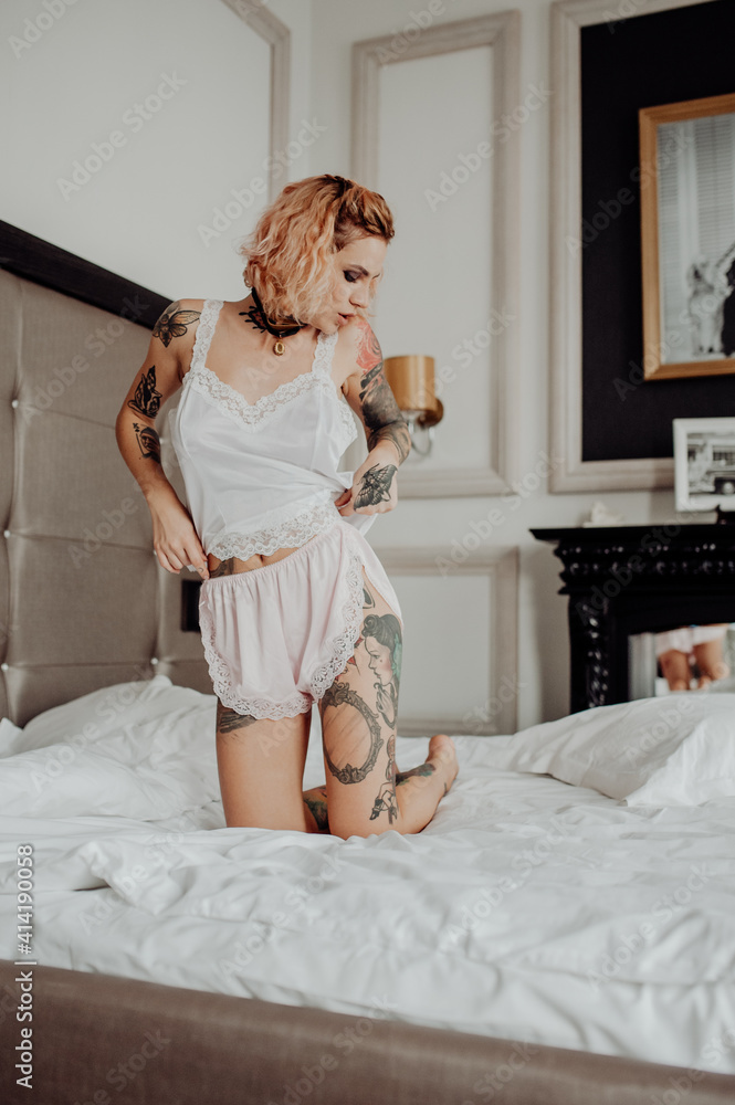 Portrait of a happy beautiful girl with tattoos. The woman is lying in bed.