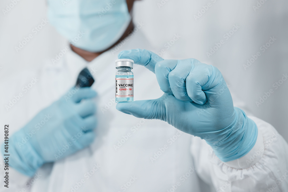 A doctor or scientist in the COVID-19 medical vaccine research and development laboratory holds a syringe with a liquid vaccine to study and analyze antibody samples for the patient. A doctor or scientist in the COVID-19 medical vaccine research and development laboratory holds a syringe with a liquid vaccine to study and analyze antibody samples for the patient.
