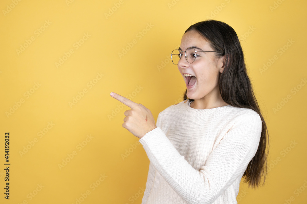 Beautiful child girl wearing casual clothes smiling and pointing with hand and finger to the side Beautiful child girl wearing casual clothes smiling and pointing with hand and finger to the side