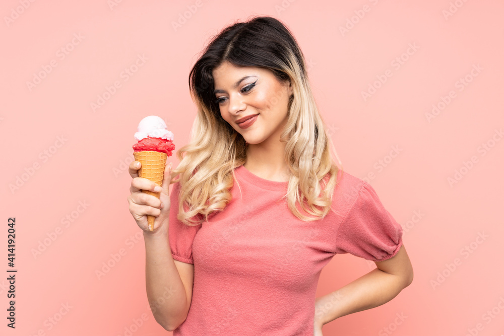 Teenager girl holding a cornet ice cream isolated on pink background with happy expression Teenager girl holding a cornet ice cream isolated on pink background with happy expression