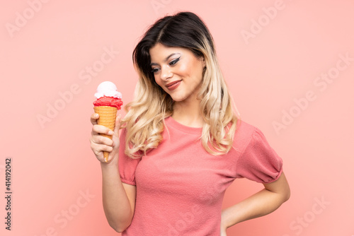 Teenager girl holding a cornet ice cream isolated on pink background with happy expression