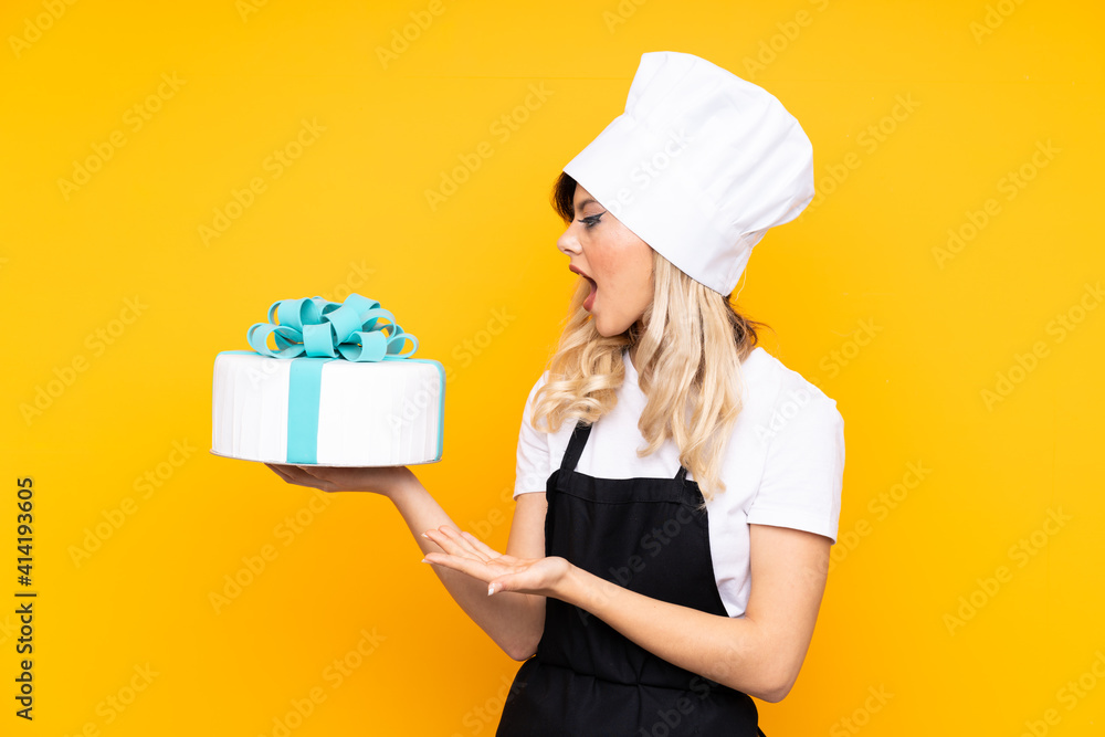 Teenager girl pastry holding a big cake isolated on yellow background holding copyspace imaginary on the palm Teenager girl pastry holding a big cake isolated on yellow background holding copyspace imaginary on the palm