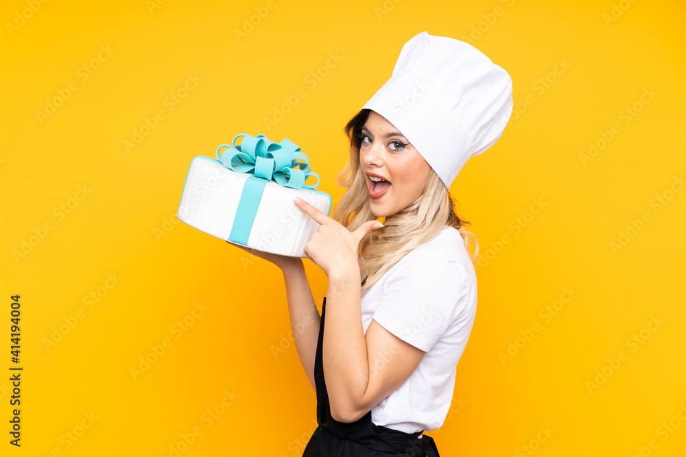 Teenager girl pastry holding a big cake isolated on yellow background Teenager girl pastry holding a big cake isolated on yellow background