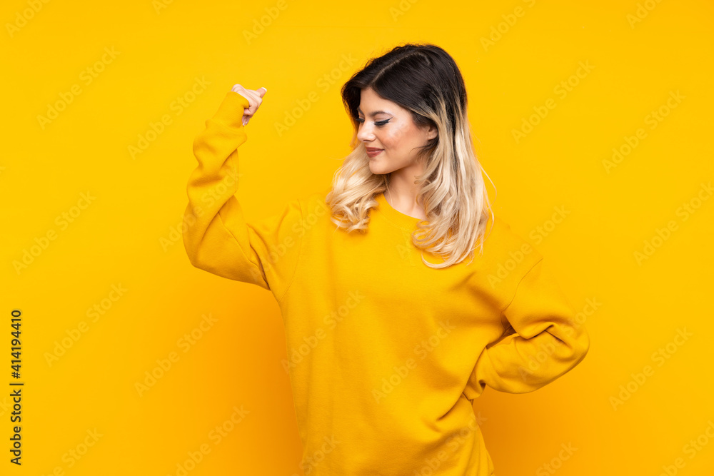 Teenager girl isolated on yellow background doing strong gesture Teenager girl isolated on yellow background doing strong gesture