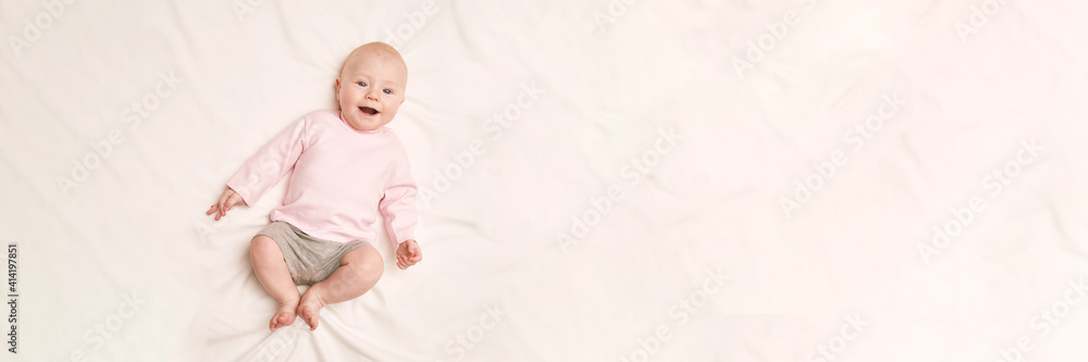 Cute small boy lying at bed. Childhood concept. Light background. Smiling child. Happy emotion. Copyspace. Stay home. Dress mockup. Children clothes. Horizontal banner Cute small boy lying at bed. Childhood concept. Light background. Smiling child. Happy emotion. Copyspace. Stay home. Dress mockup. Children clothes. Horizontal banner