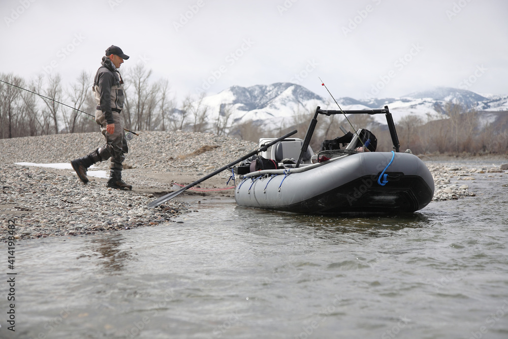 Naklejka premium fly fisherman walking to pontoon raft on a river