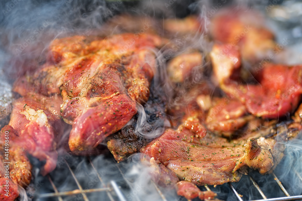 Delicious piece of pork neck roasting on the grill during preparation. Closeup macro of Pork steak meat with smoke on barbecue grill. Delicious piece of pork neck roasting on the grill during preparation. Closeup macro of Pork steak meat with smoke on barbecue grill.