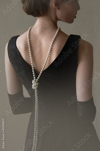 Beautiful woman figure in profile in a black dress and pearls in the style of 20-30 years of the XX century