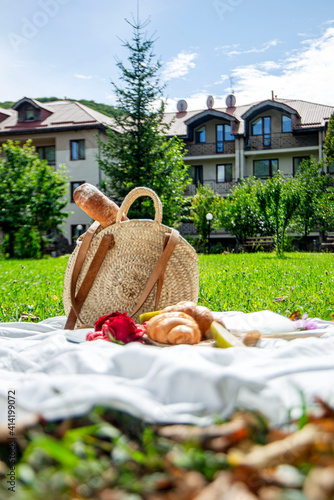 picnic basket with bread and fruits, wicker basket with food for a romantic picnic on a white blanket in the park, lunch on the lawn, snack on the street