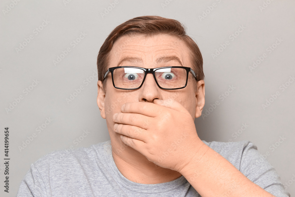 Portrait of shocked frightened man covering mouth with hand Portrait of shocked frightened man covering mouth with hand