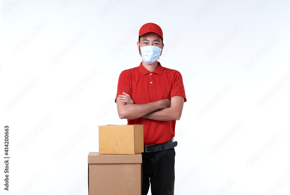 Asian delivery man wearing face mask in red uniform and parcel box isolated over white background. social distancing and new normal concept. Asian delivery man wearing face mask in red uniform and parcel box isolated over white background. social distancing and new normal concept.