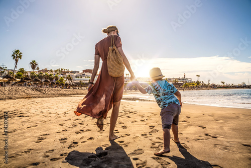 Family holiday on Tenerife, Spain. Mother with son walking on the sandy beach. Positive human emotions, active lifestyles.