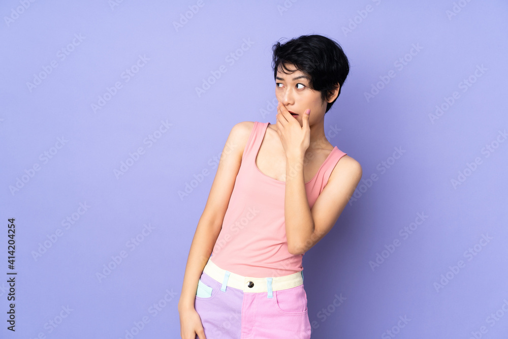 Young Vietnamese woman with short hair over isolated purple background doing surprise gesture while looking to the side Young Vietnamese woman with short hair over isolated purple background doing surprise gesture while looking to the side