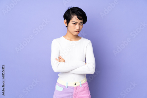 Young Vietnamese woman with short hair over isolated purple background feeling upset