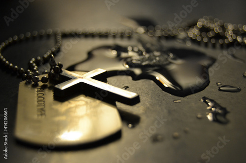 Photography Closeup shot of a chain with a cross and a dog tag on a wet table