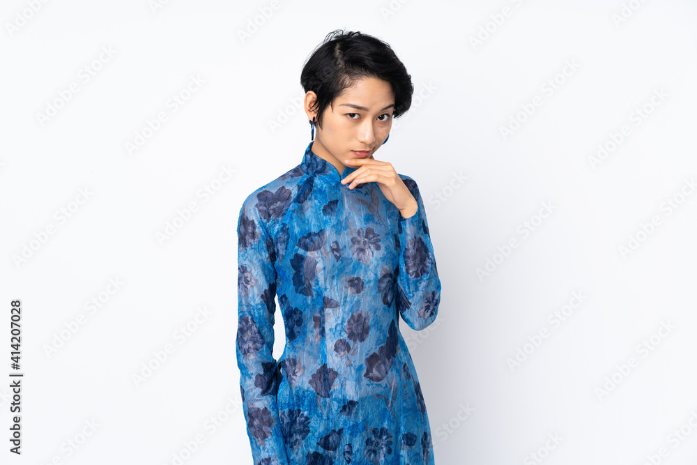 Young Vietnamese woman with short hair wearing a traditional dress over isolated white background thinking Young Vietnamese woman with short hair wearing a traditional dress over isolated white background thinking