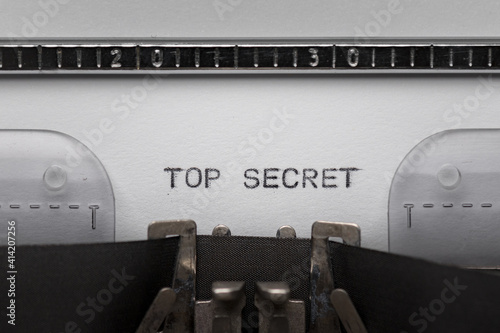 Typing text TOP SECRET on vintage manual typewriter. Close up of writes word on white paper. Shot in macro.