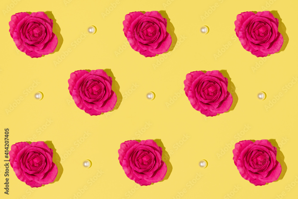 Creative pattern made with  magenta colored rose and white pearls on bright yellow background. Minimal aesthetic flat lay. Romantic creative idea. Spring or summer concept with bloom.