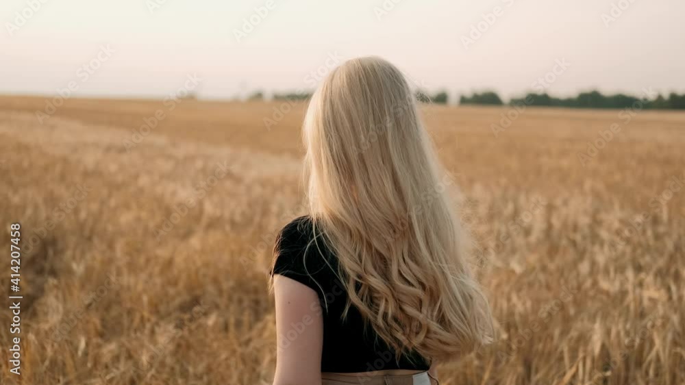 Joyful young girl enjoying nature and warm sunlight outdoors. Happy blondy woman walking and smiling in wheat field during sunny summer day. Healthy natural organic lifestyle. Joyful young girl enjoying nature and warm sunlight outdoors. Happy blondy woman walking and smiling in wheat field during sunny summer day. Healthy natural organic lifestyle.