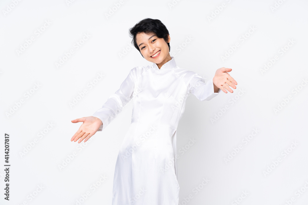 Young Vietnamese woman with short hair wearing a traditional dress over isolated white background presenting and inviting to come with hand Young Vietnamese woman with short hair wearing a traditional dress over isolated white background presenting and inviting to come with hand
