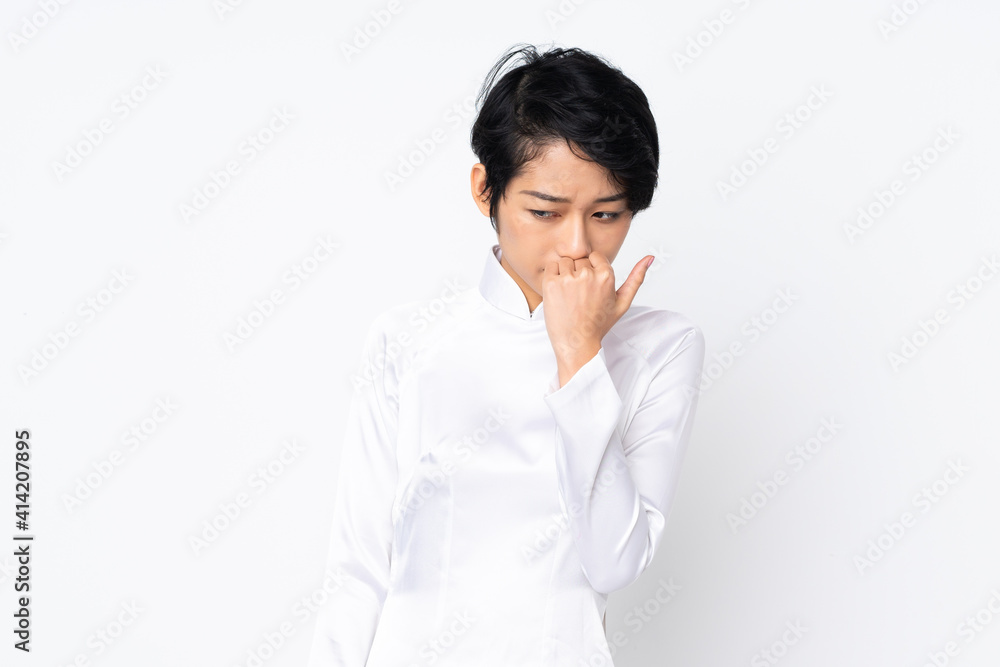 Young Vietnamese woman with short hair wearing a traditional dress over isolated white background having doubts Young Vietnamese woman with short hair wearing a traditional dress over isolated white background having doubts