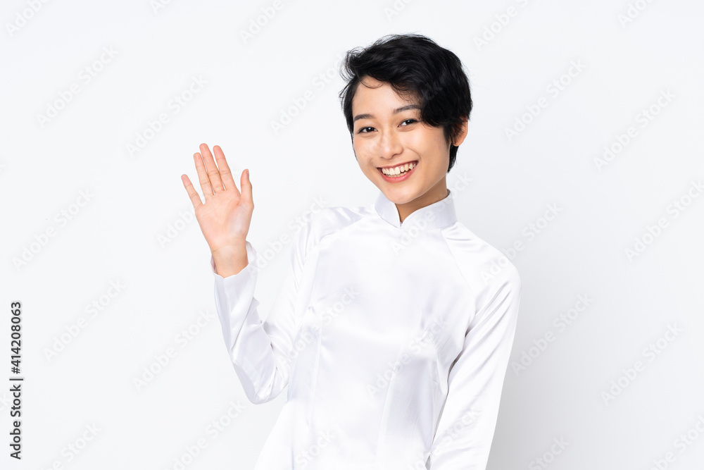 Young Vietnamese woman with short hair wearing a traditional dress over isolated white background saluting with hand with happy expression Young Vietnamese woman with short hair wearing a traditional dress over isolated white background saluting with hand with happy expression
