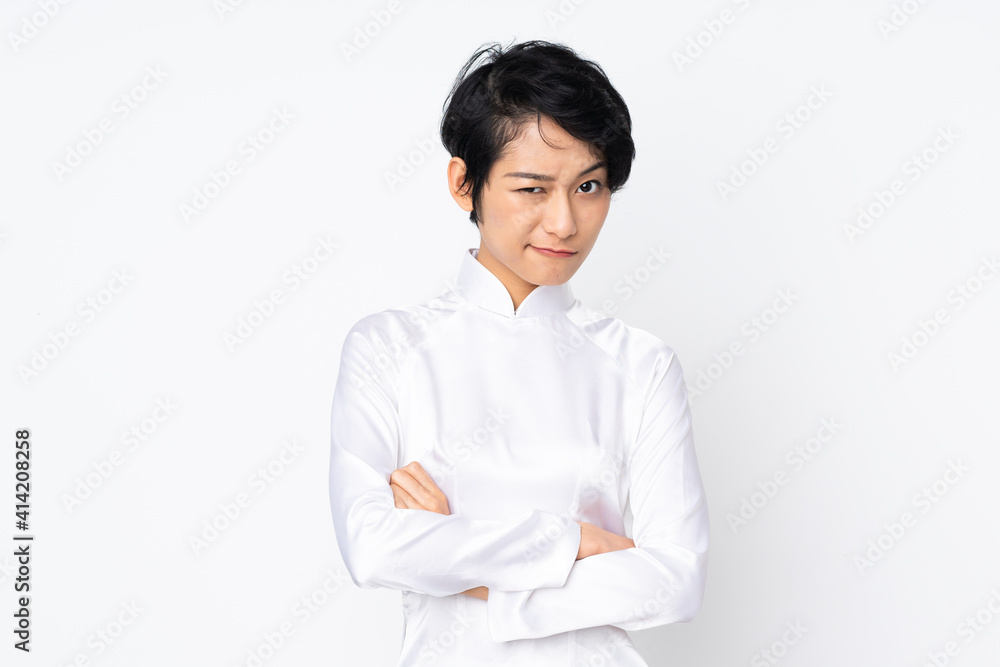 Young Vietnamese woman with short hair wearing a traditional dress over isolated white background feeling upset Young Vietnamese woman with short hair wearing a traditional dress over isolated white background feeling upset