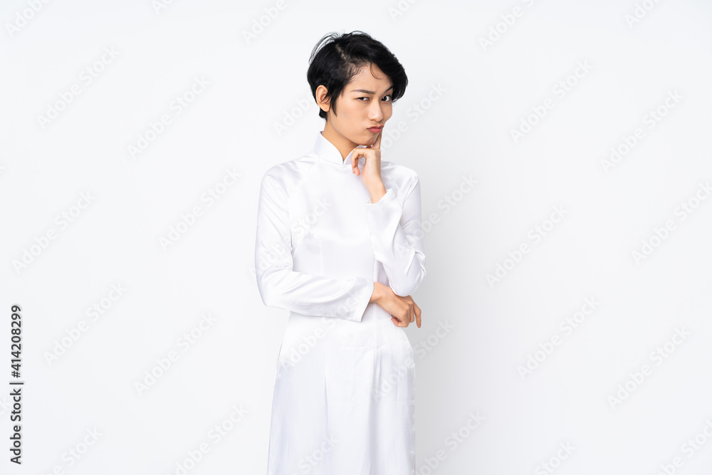 Young Vietnamese woman with short hair wearing a traditional dress over isolated white background and thinking Young Vietnamese woman with short hair wearing a traditional dress over isolated white background and thinking