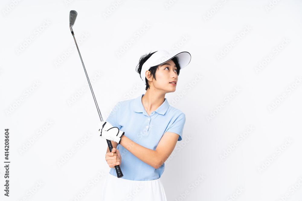Young Vietnamese golfer woman over isolated white wall playing golf Young Vietnamese golfer woman over isolated white wall playing golf