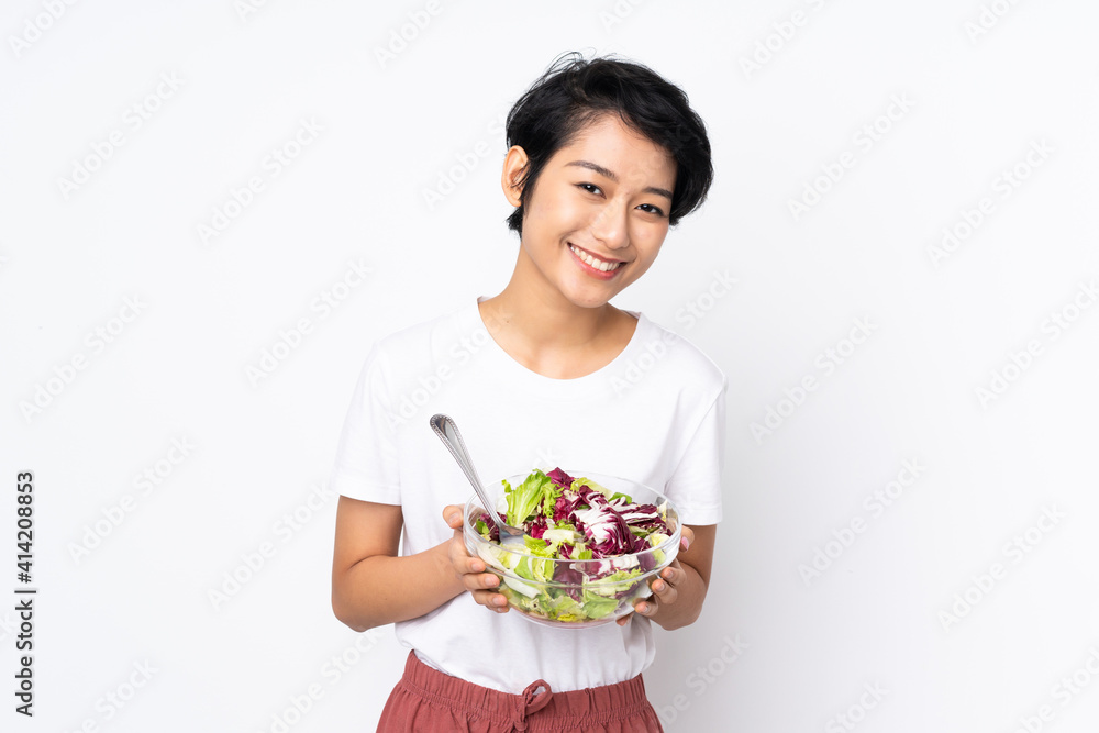 Young Vietnamese woman with short hair holding a salad over isolated background Young Vietnamese woman with short hair holding a salad over isolated background