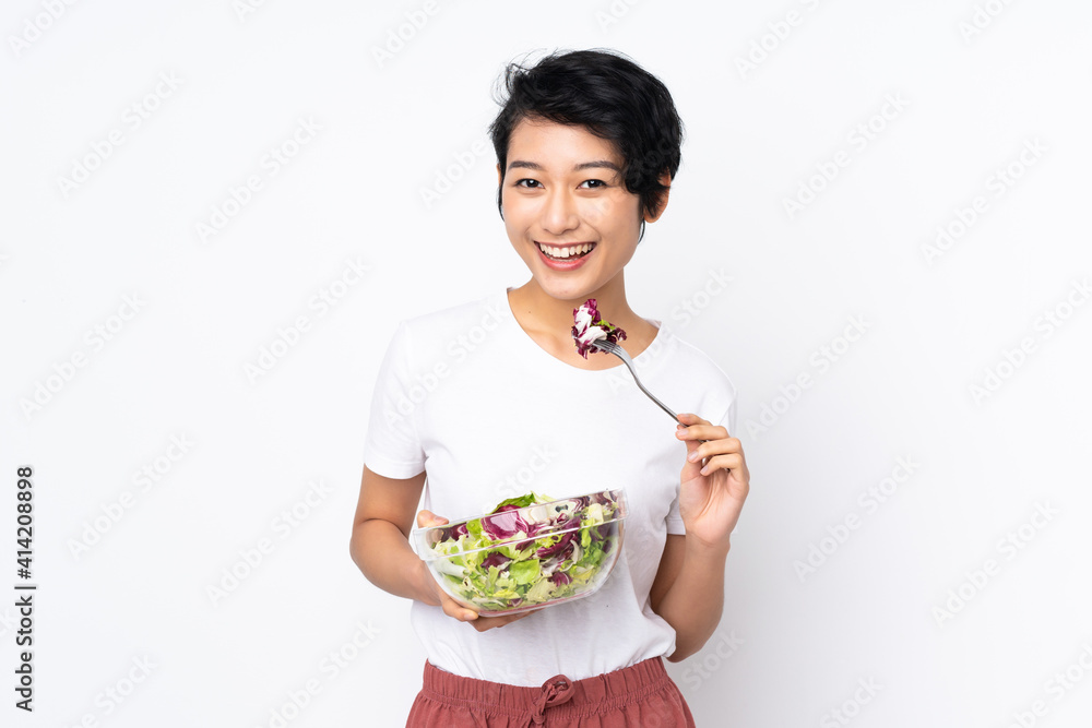 Young Vietnamese woman with short hair holding a salad over isolated background Young Vietnamese woman with short hair holding a salad over isolated background