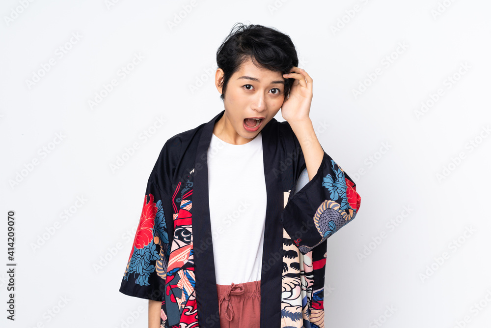 Young Vietnamese woman with short hair wearing a traditional dress over isolated white background with surprise and shocked facial expression Young Vietnamese woman with short hair wearing a traditional dress over isolated white background with surprise and shocked facial expression