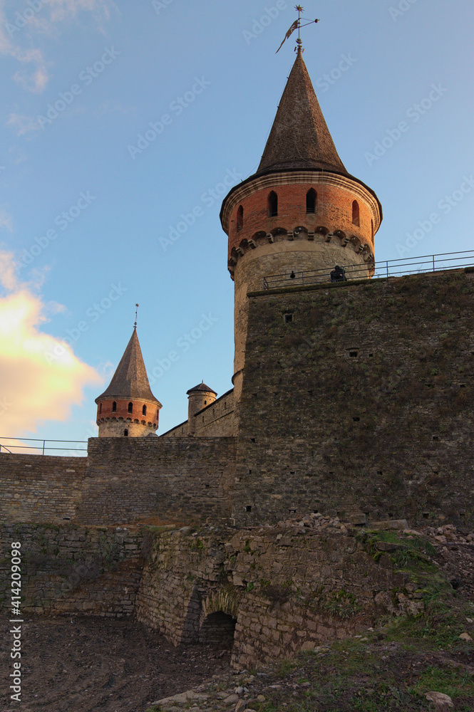 Scenic landscape photo of ancient Kamianets-Podilskyi Castle. High and thick stone walls with towers against blue sky. Abstract photo of stone walls. Ukraine