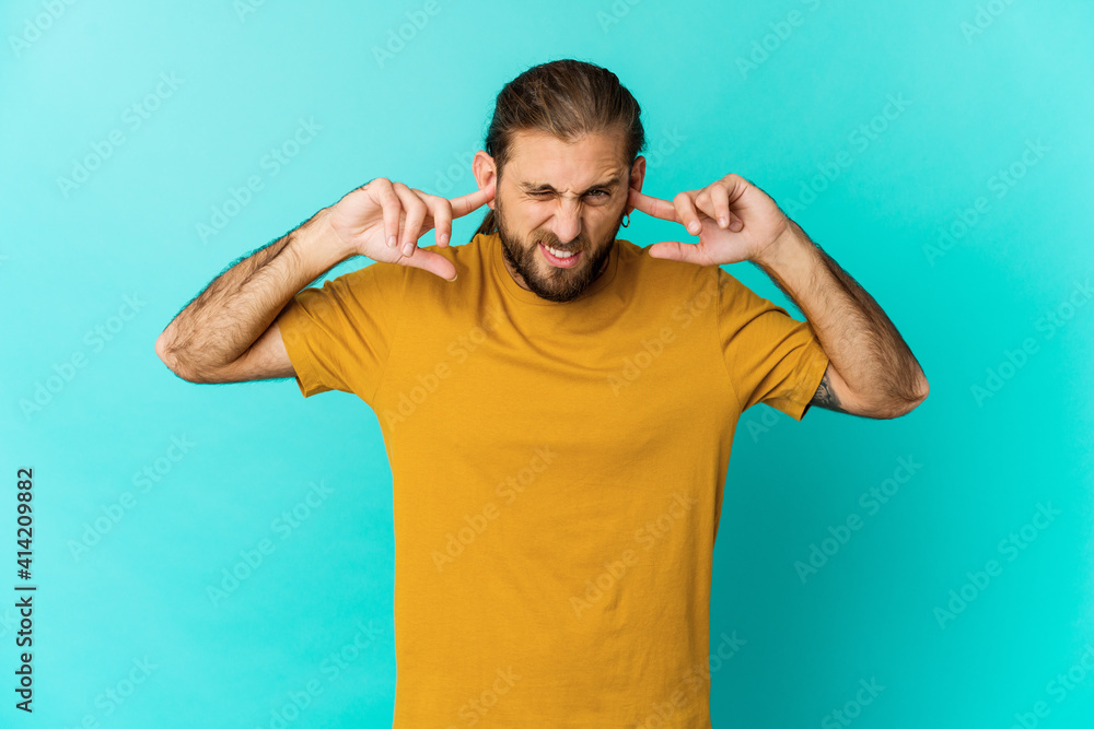 Young man with long hair look covering ears with fingers, stressed and desperate by a loudly ambient. Young man with long hair look covering ears with fingers, stressed and desperate by a loudly ambient.