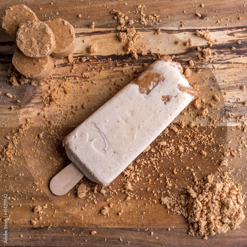 Sweet peanut popsicle, mexican paleta, on a wooden plate with crumbs photo