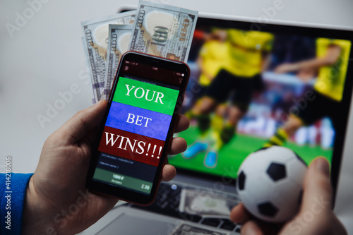 Smartphone with victory message and male's hand with soccer ball. Sport and betting concept. photo